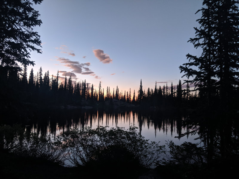 A mountain lake at sunset with trees reflected in the water